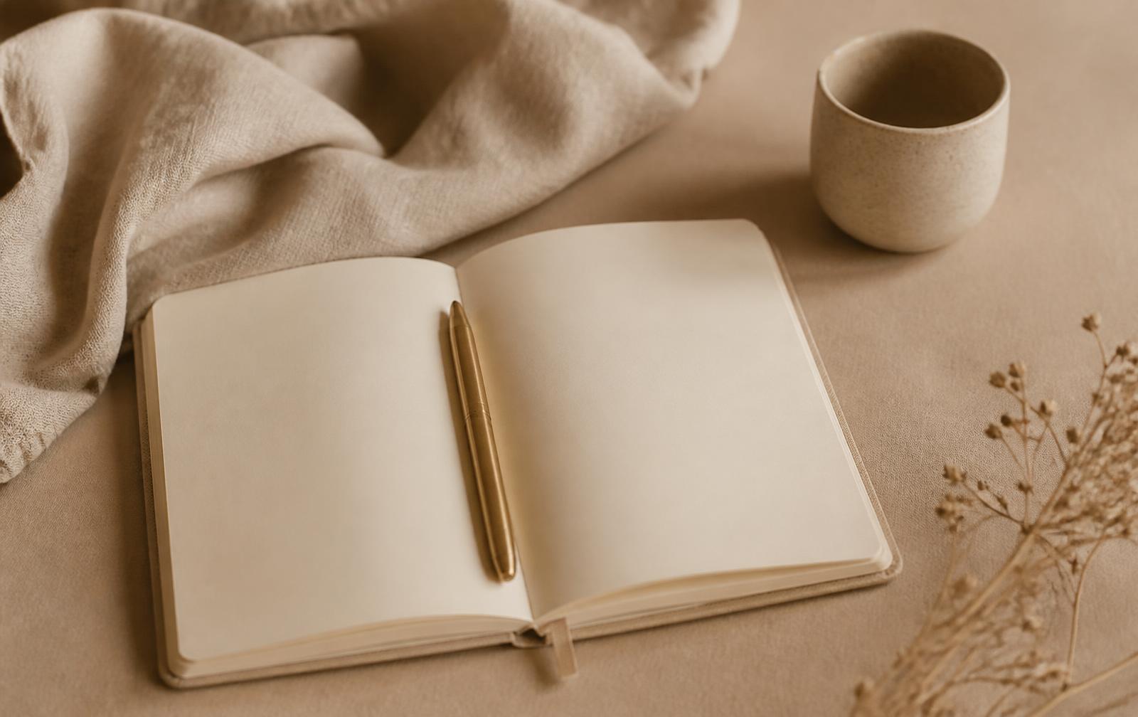 Caderno aberto com caneta sobre mesa em tons neutros